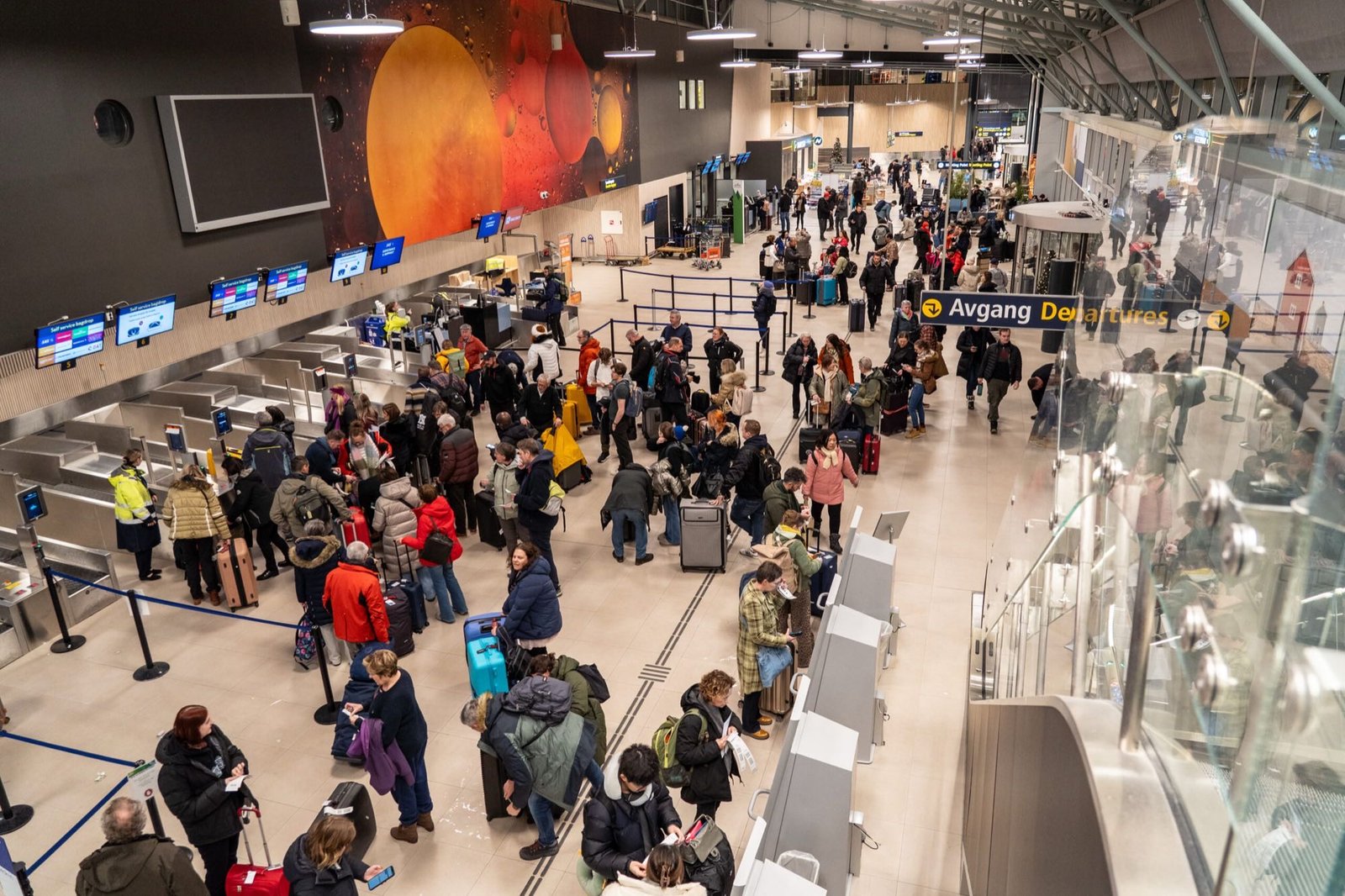 Fullt av reisende med kofferter i avgangshallen på en flyplass i nord